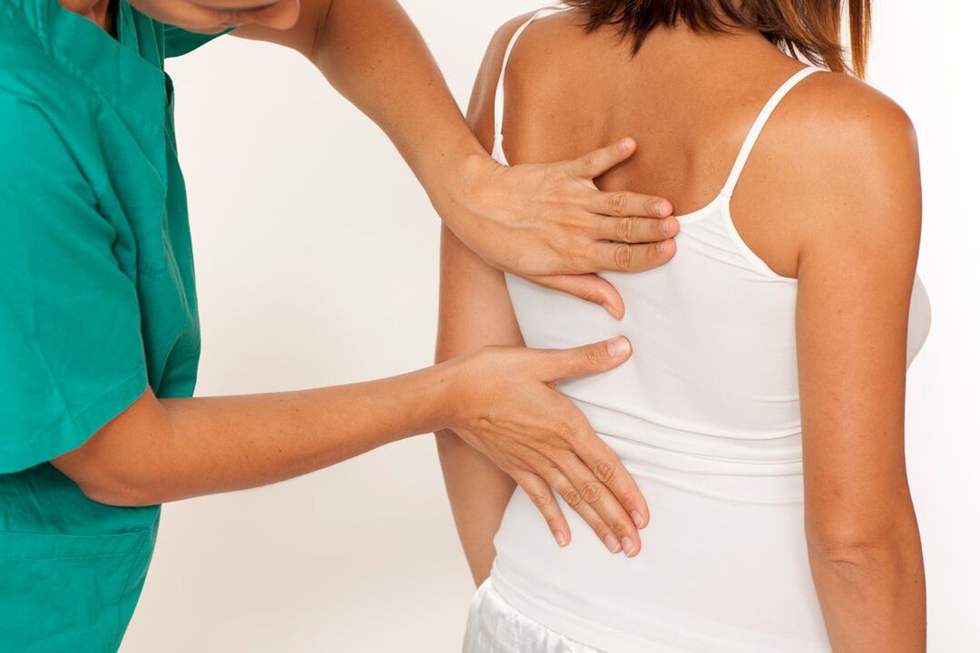 de arts onderzoekt de rug op pijn in het gebied van de schouderbladen
